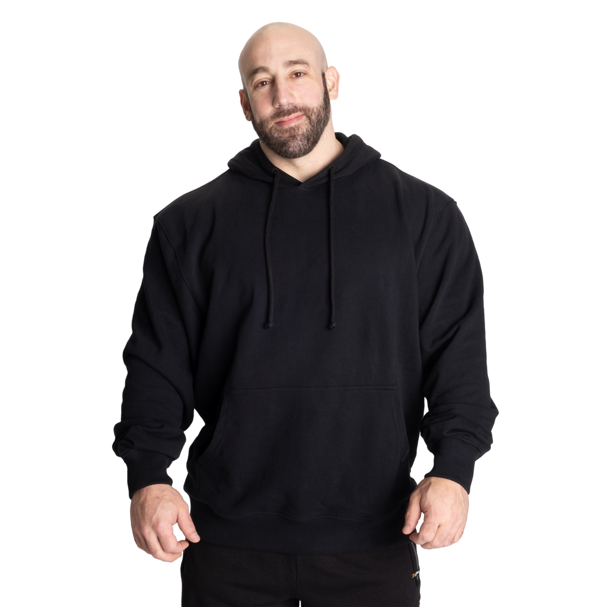 A man wearing a plain black pullover hoodie with drawstrings and a front kangaroo pocket, standing against a solid white background.