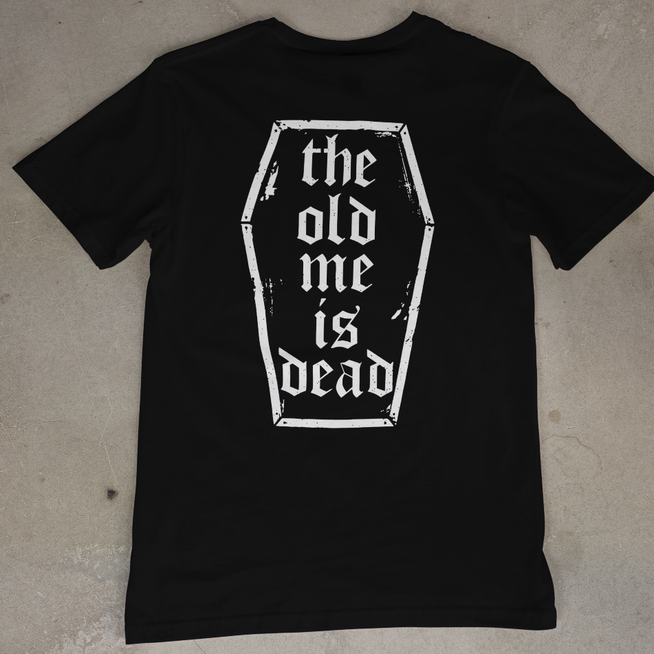 Black t-shirt with 'the old me is dead' design on a beige surface