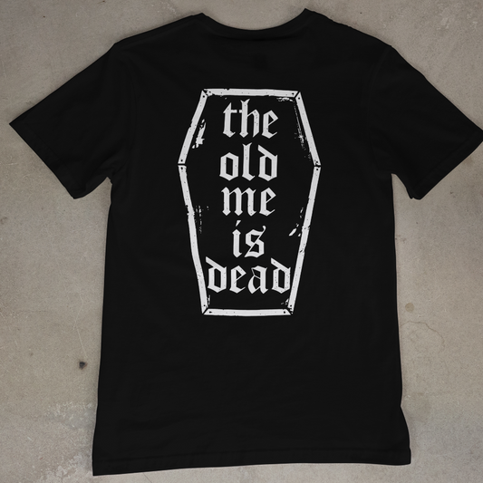 Black t-shirt with 'the old me is dead' design on a beige surface